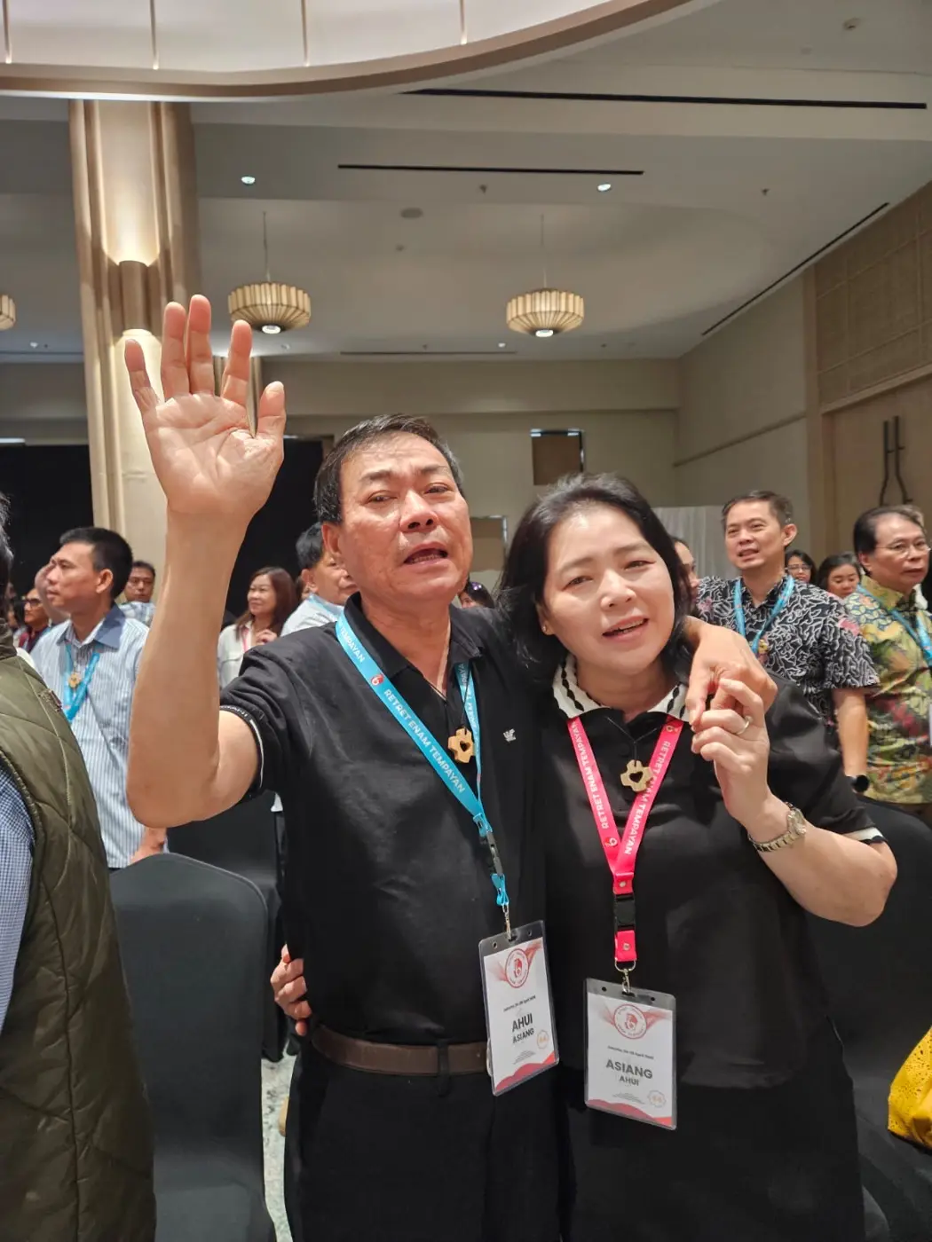 Suami-istri alumni berdoa bersama dengan tangan terangkat